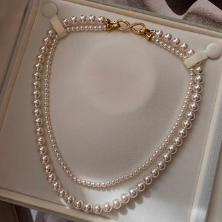 Elegant dual-strand pearl necklace with gold infinity clasp. Wear together or separately. Versatile layered design perfect for everyday elegance & special occasions.