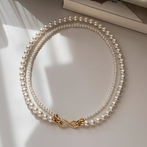 Elegant dual-strand pearl necklace with gold infinity clasp. Wear together or separately. Versatile layered design perfect for everyday elegance & special occasions.