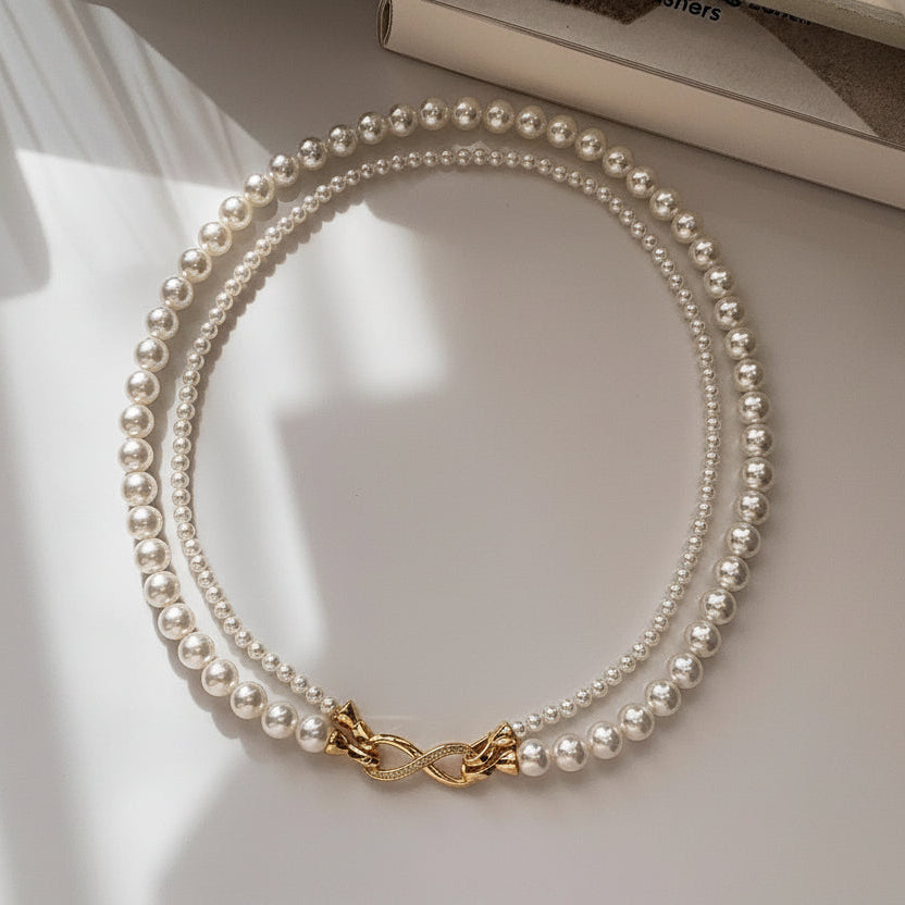 Elegant dual-strand pearl necklace with gold infinity clasp. Wear together or separately. Versatile layered design perfect for everyday elegance & special occasions.