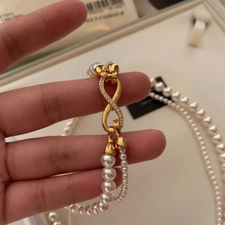 Elegant dual-strand pearl necklace with gold infinity clasp. Wear together or separately. Versatile layered design perfect for everyday elegance & special occasions.