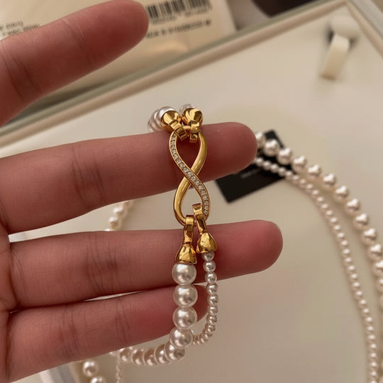 Elegant dual-strand pearl necklace with gold infinity clasp. Wear together or separately. Versatile layered design perfect for everyday elegance & special occasions.