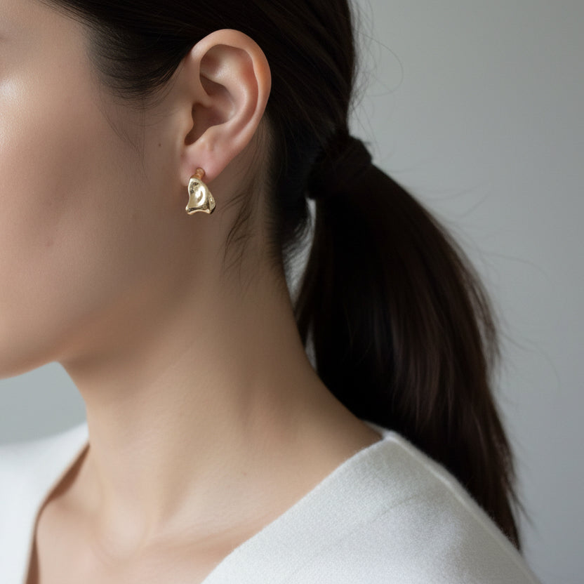 Artful gold sculpted stud earrings with organic pebble shape. Lightweight, polished finish. Perfect for everyday elegance & creative style.