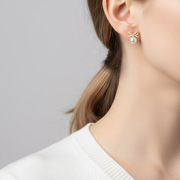 Elegant gold bow stud earrings with white pearls & cubic zirconia. Lightweight, playful design. Perfect for everyday charm & special occasions.
