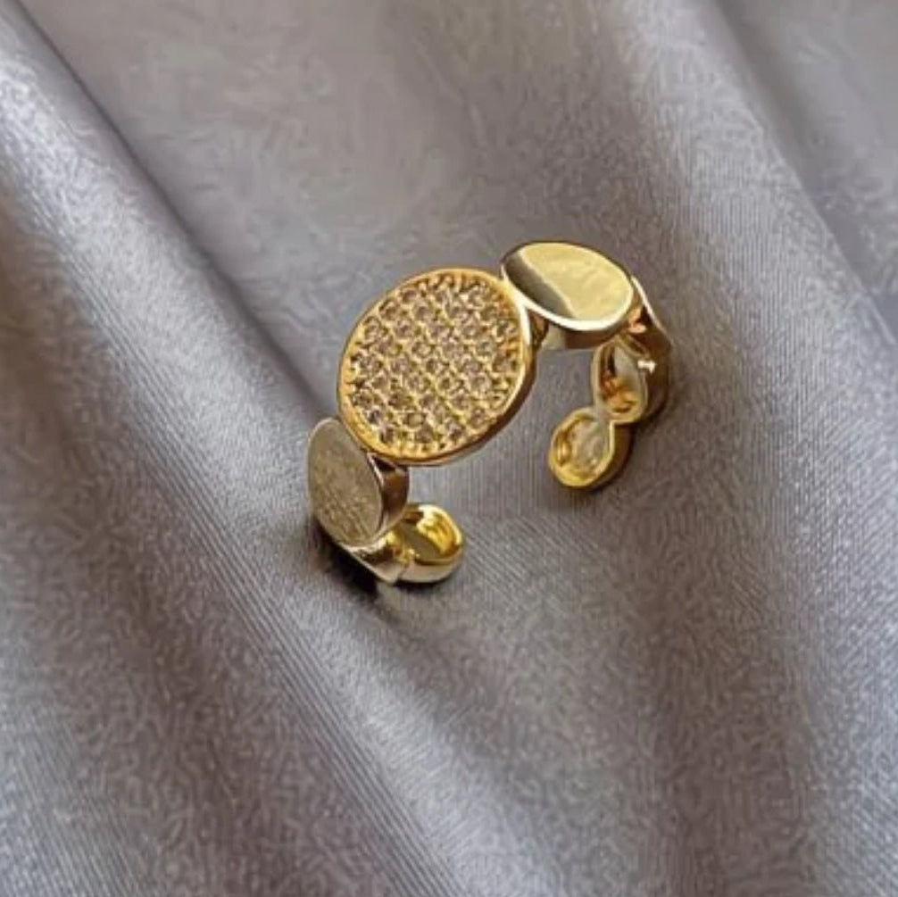 Modern gold disc ring with pavé cubic zirconia. Adjustable sculptural design, stackable. Perfect for statement style & everyday elegance.