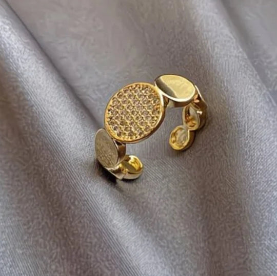 Modern gold disc ring with pavé cubic zirconia. Adjustable sculptural design, stackable. Perfect for statement style & everyday elegance.