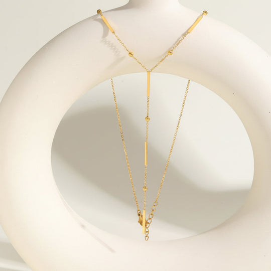 Elegant gold Y-shaped fringe necklace with square beads & pearls. Stainless steel, layered design. Perfect for everyday elegance & modern style.