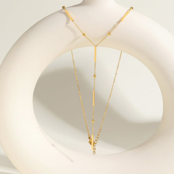 Elegant gold Y-shaped fringe necklace with square beads & pearls. Stainless steel, layered design. Perfect for everyday elegance & modern style.