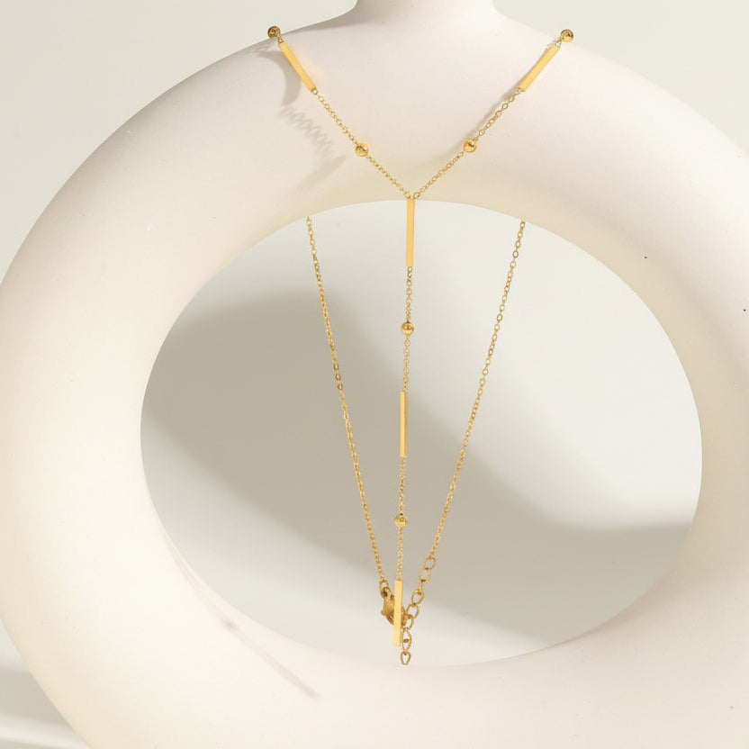 Elegant gold Y-shaped fringe necklace with square beads & pearls. Stainless steel, layered design. Perfect for everyday elegance & modern style.